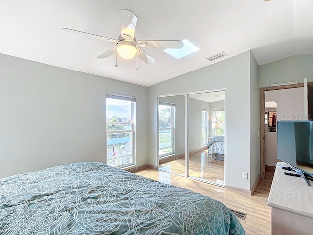 bedroom featuring lofted ceiling, multiple windows, light hardwood / wood-style floors, and ceiling fan