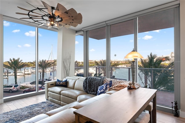 sunroom with a wealth of natural light, ceiling fan, and a water view