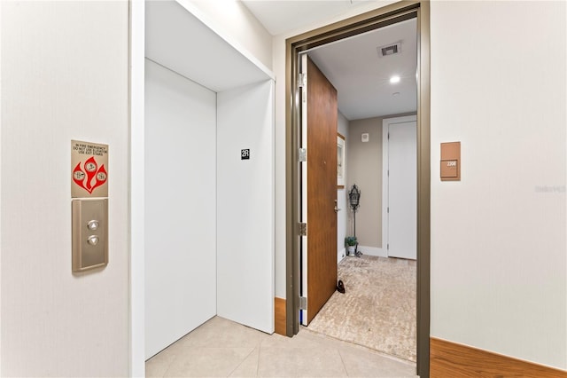 hall featuring light tile patterned floors and elevator