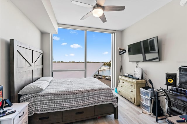 bedroom with light hardwood / wood-style flooring, expansive windows, and ceiling fan