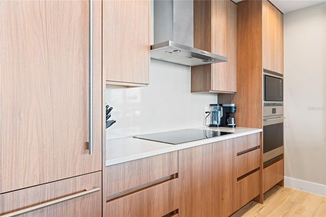 kitchen with appliances with stainless steel finishes, light brown cabinetry, light hardwood / wood-style floors, and wall chimney range hood