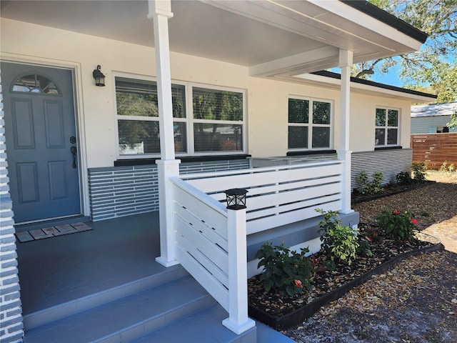 view of exterior entry with fence and stucco siding