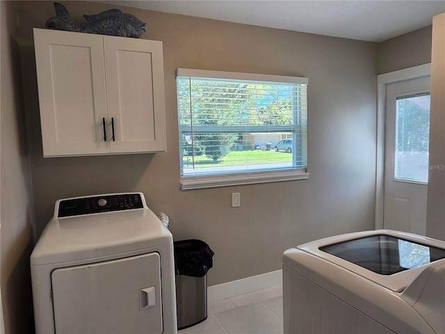 washroom with cabinet space, light tile patterned floors, baseboards, and washer and clothes dryer