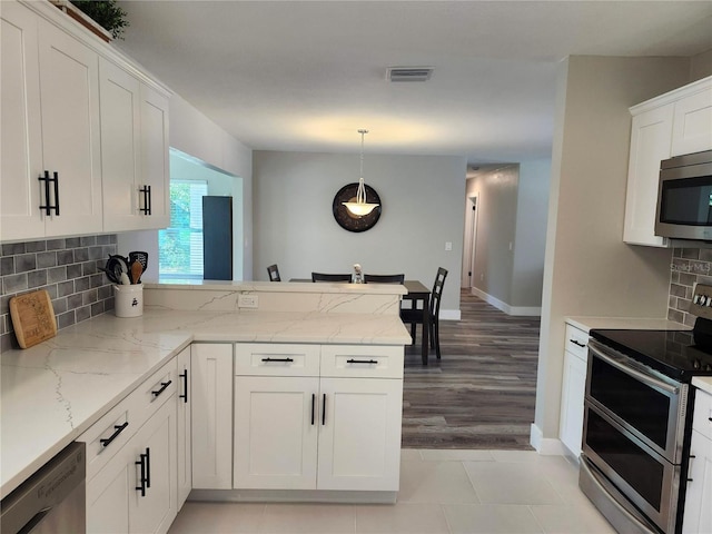 kitchen featuring visible vents, backsplash, appliances with stainless steel finishes, white cabinetry, and a peninsula