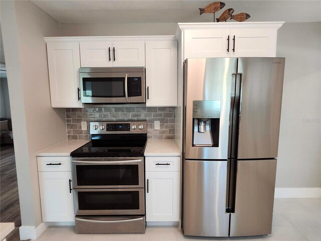 kitchen with stainless steel appliances, light countertops, backsplash, and white cabinetry