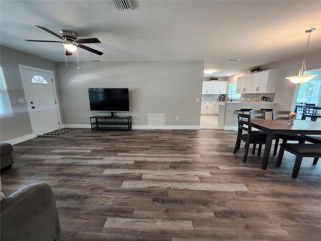 living room featuring dark wood-style floors, visible vents, and baseboards