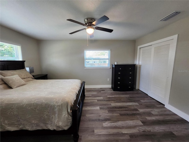 bedroom featuring dark wood-style floors, a closet, visible vents, ceiling fan, and baseboards