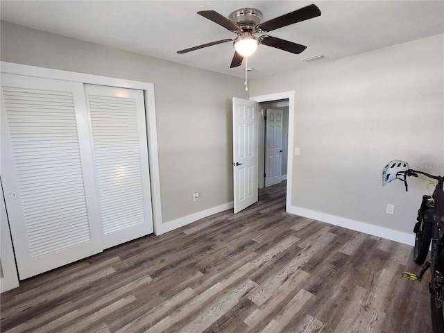 unfurnished bedroom with a closet, wood finished floors, visible vents, and baseboards