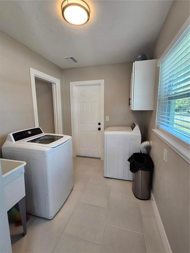 laundry room featuring cabinet space, light tile patterned floors, baseboards, visible vents, and separate washer and dryer