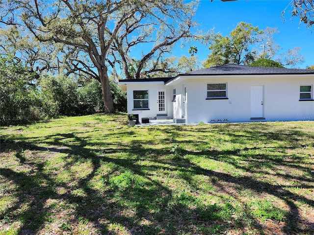 view of front of property with stucco siding, a patio, and a front yard