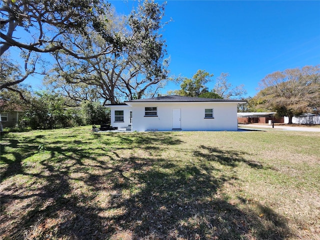 rear view of property with a lawn and stucco siding