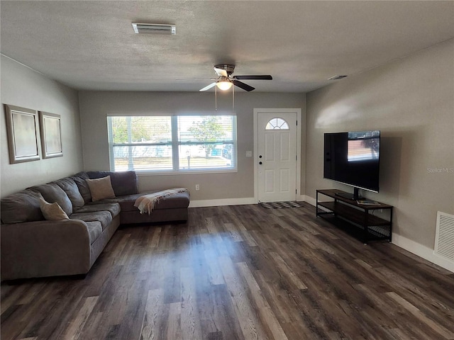 living area with a textured ceiling, visible vents, and dark wood-style flooring