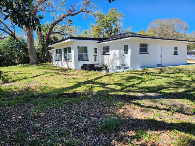 back of house featuring a lawn and stucco siding