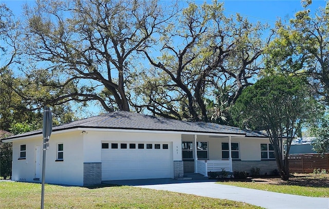 single story home with an attached garage, brick siding, concrete driveway, stucco siding, and a front yard