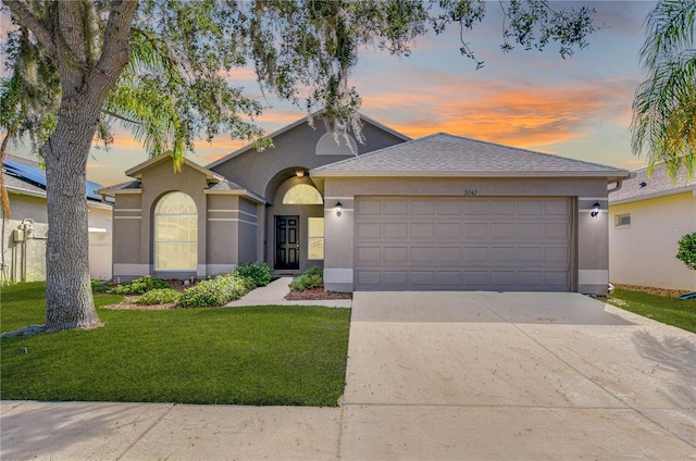 ranch-style house with a garage and a lawn