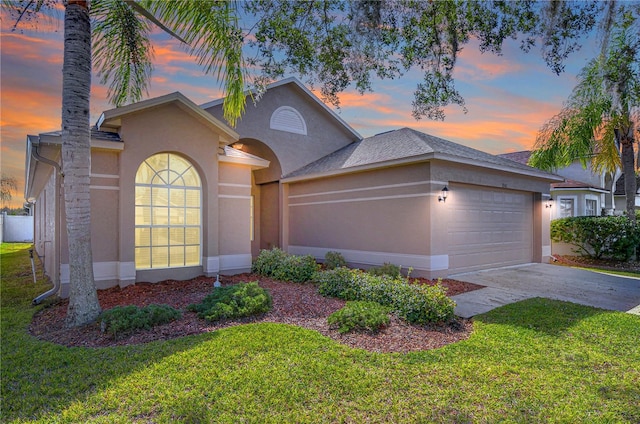 view of front of property featuring driveway, a front lawn, an attached garage, and stucco siding