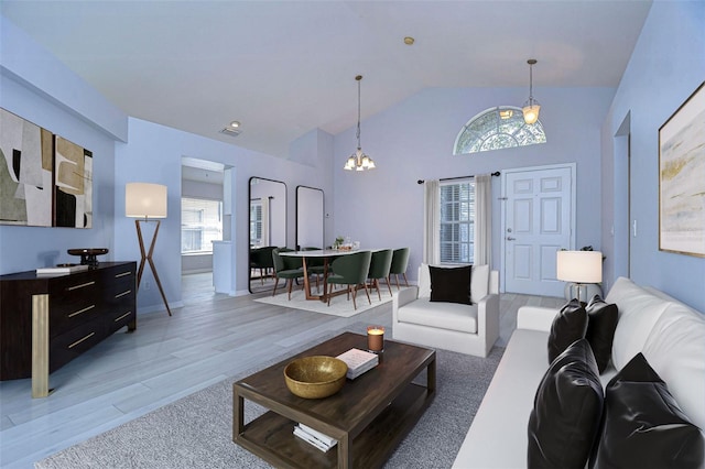 living room featuring light wood-style floors, visible vents, high vaulted ceiling, and an inviting chandelier