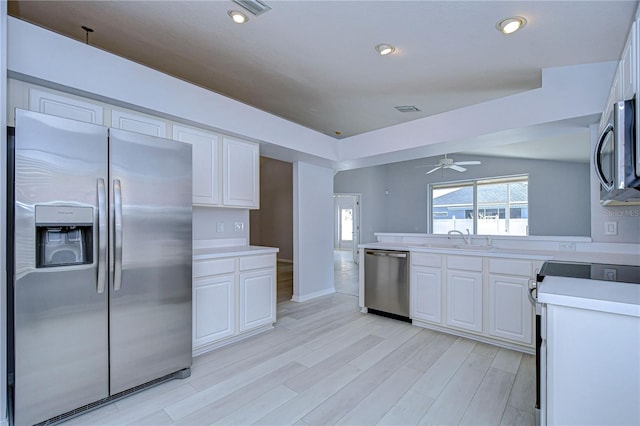 kitchen featuring light wood finished floors, light countertops, appliances with stainless steel finishes, white cabinetry, and a sink