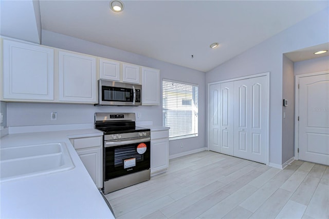 kitchen featuring light countertops, light wood-style flooring, appliances with stainless steel finishes, white cabinetry, and a sink