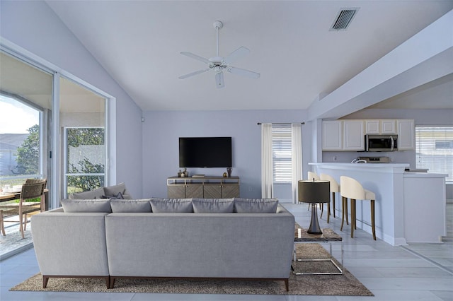 living room featuring lofted ceiling, visible vents, and plenty of natural light