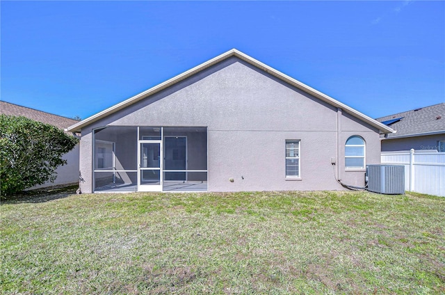 rear view of house with a lawn, stucco siding, fence, and central air condition unit