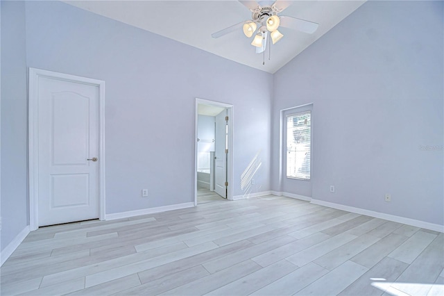 empty room featuring high vaulted ceiling, light wood finished floors, a ceiling fan, and baseboards