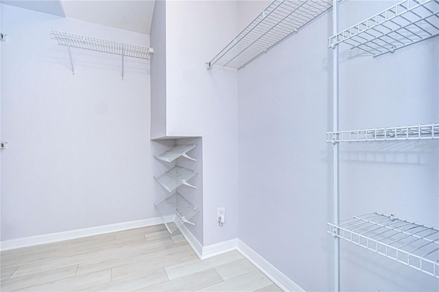 walk in closet with wood finished floors