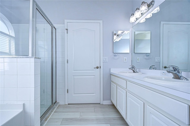 full bath with double vanity, a sink, a shower stall, and a bath