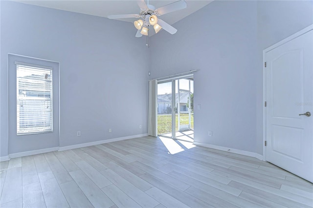 empty room featuring light wood-type flooring, a high ceiling, and baseboards