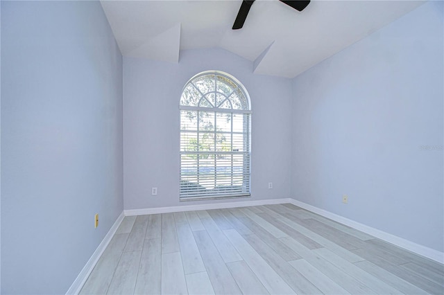 spare room featuring lofted ceiling, light wood finished floors, a ceiling fan, and baseboards