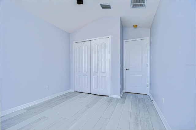 unfurnished bedroom with lofted ceiling, a closet, visible vents, and light wood finished floors