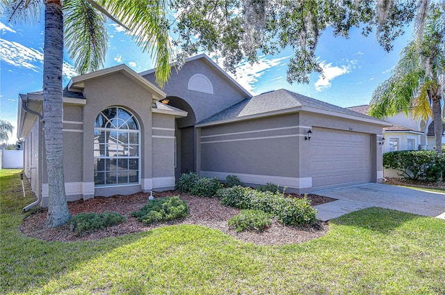 view of front of house with a front yard, concrete driveway, an attached garage, and stucco siding