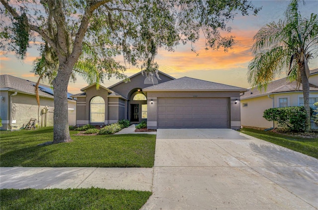 single story home featuring concrete driveway, a lawn, an attached garage, and stucco siding