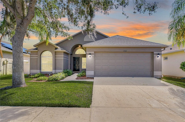 ranch-style home featuring a garage, driveway, a front yard, and stucco siding