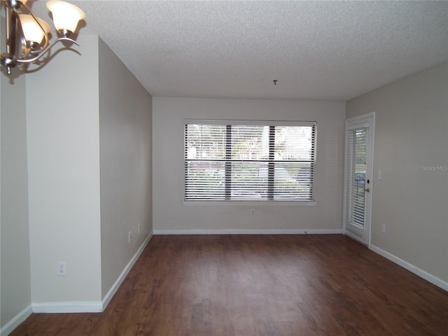 unfurnished room featuring a notable chandelier, dark wood-type flooring, and a textured ceiling