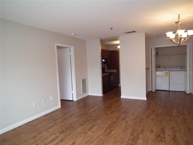 unfurnished living room with washing machine and dryer, dark wood-type flooring, a textured ceiling, and an inviting chandelier