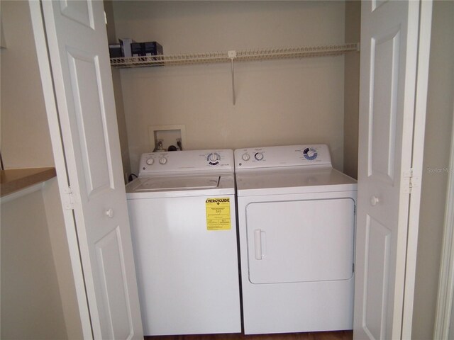 laundry area with hardwood / wood-style flooring and washing machine and dryer