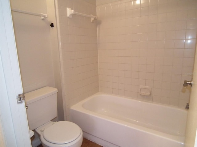 bathroom with tiled shower / bath combo and toilet