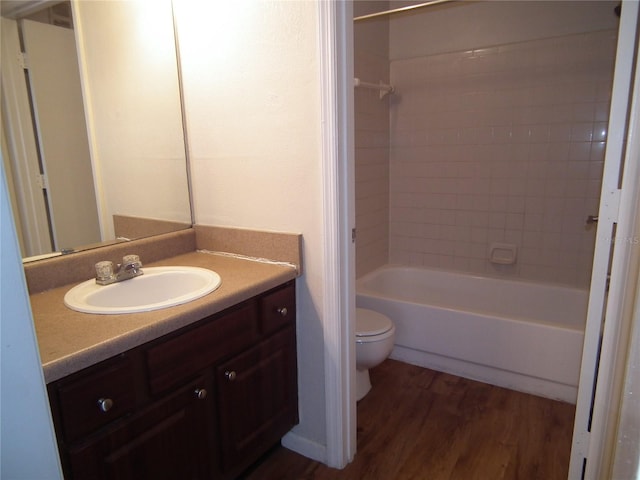 full bathroom with tiled shower / bath combo, vanity, hardwood / wood-style floors, and toilet