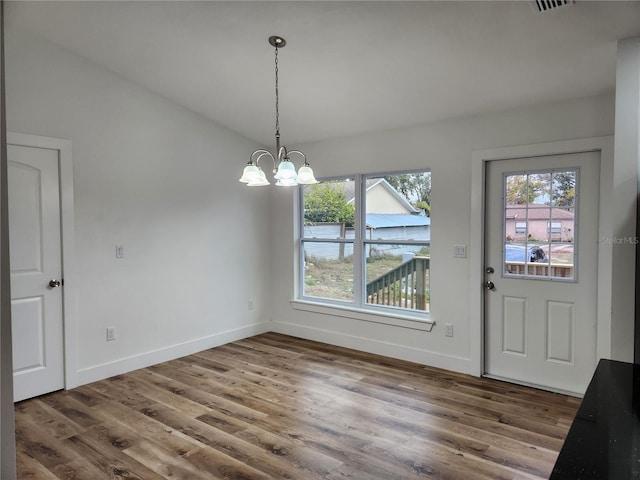 unfurnished dining area with an inviting chandelier, hardwood / wood-style flooring, and lofted ceiling