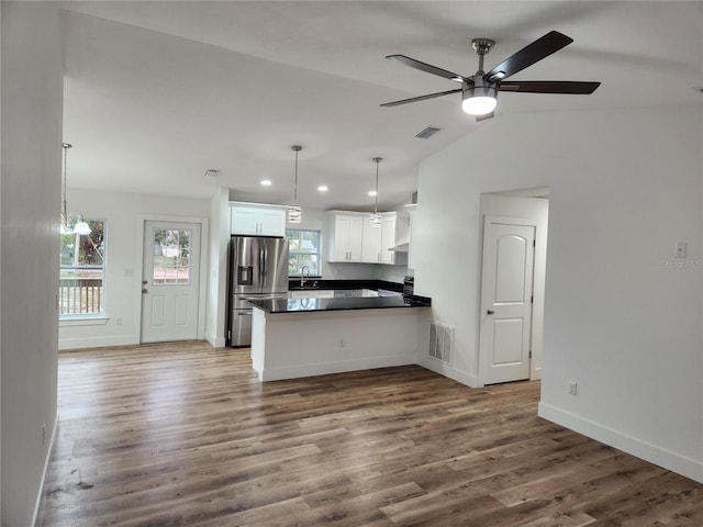 kitchen with pendant lighting, white cabinets, stainless steel fridge with ice dispenser, kitchen peninsula, and vaulted ceiling