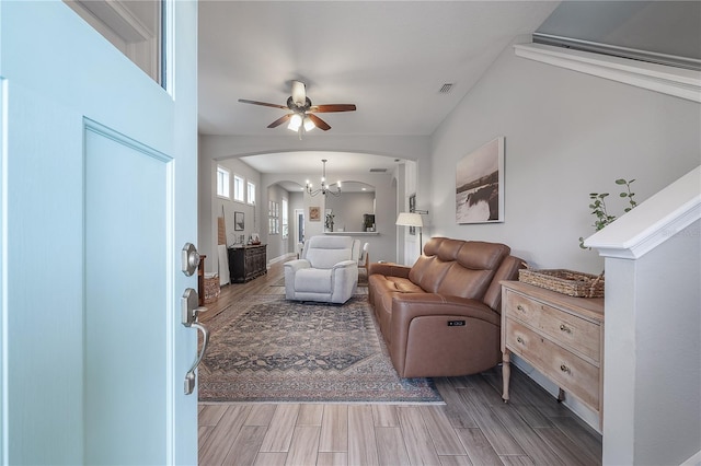 living room with ceiling fan with notable chandelier