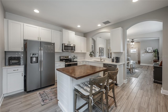 kitchen with sink, white cabinets, butcher block counters, and appliances with stainless steel finishes