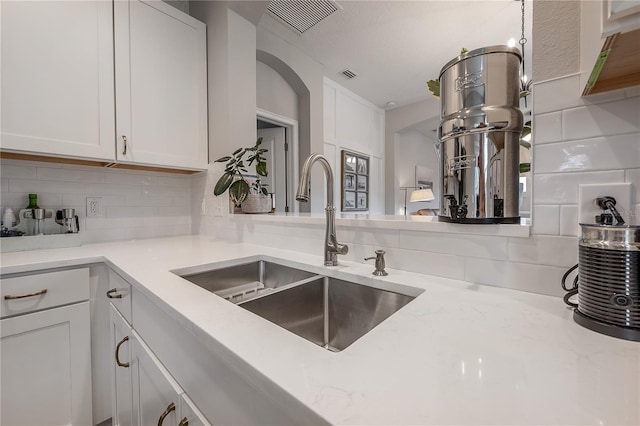 kitchen featuring sink, white cabinets, tasteful backsplash, and light stone countertops