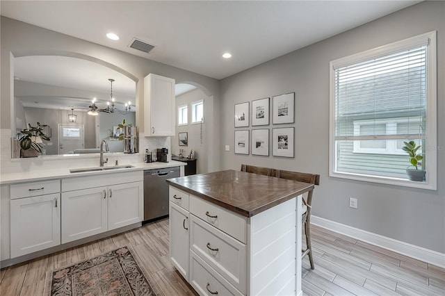 kitchen featuring sink, dishwasher, white cabinetry, and pendant lighting