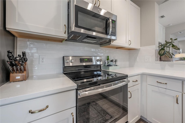 kitchen with white cabinetry, decorative backsplash, and stainless steel appliances