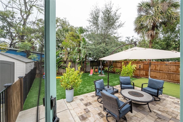 view of patio with a playground, a shed, and a fire pit