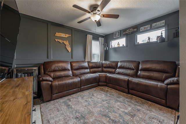 carpeted living room with a textured ceiling and ceiling fan