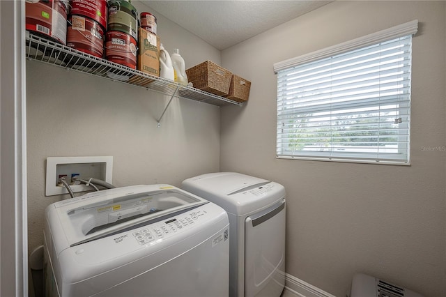 clothes washing area with washing machine and clothes dryer and a textured ceiling