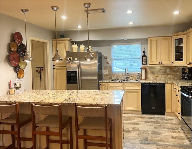 kitchen featuring sink, backsplash, black appliances, and a breakfast bar